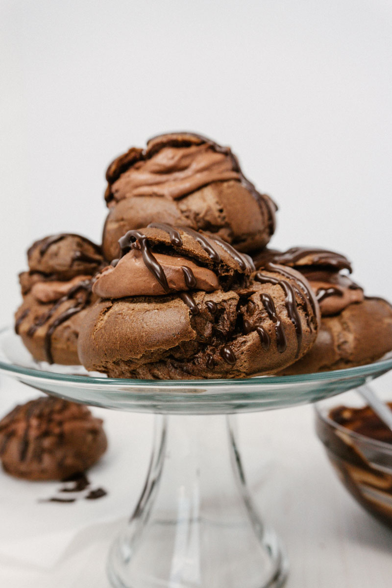 taste before beauty chocolate creme puff with best easy chocolate mousse drizzled over the top on a platter stacked