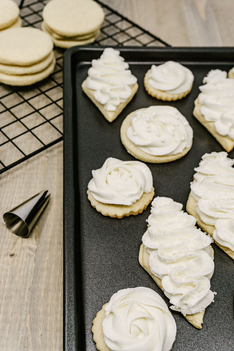 taste before beauty frosted sugar cookies on a pan with wire rack of unfrosted cookies