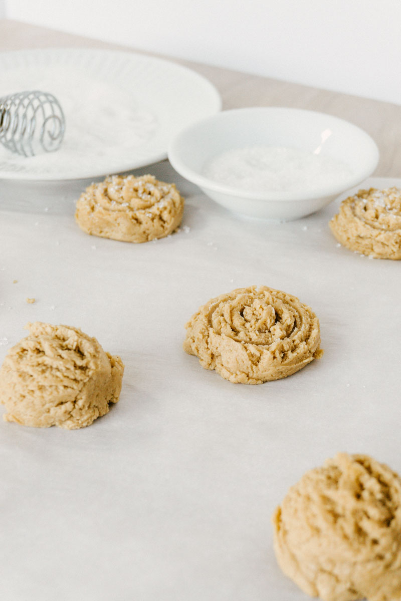 taste before beauty peanut butter cookie dough scoops on parchment paper with sugar in the back