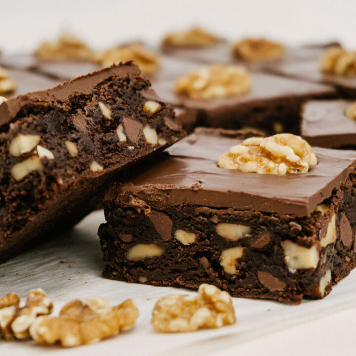 taste before beauty fudge walnut brownies stacked with each other with walnuts in the front