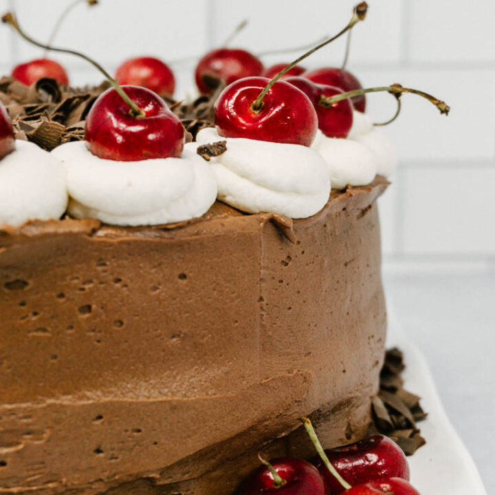 taste before beauty black forest cherry chocolate cake on a plate with cherries on top