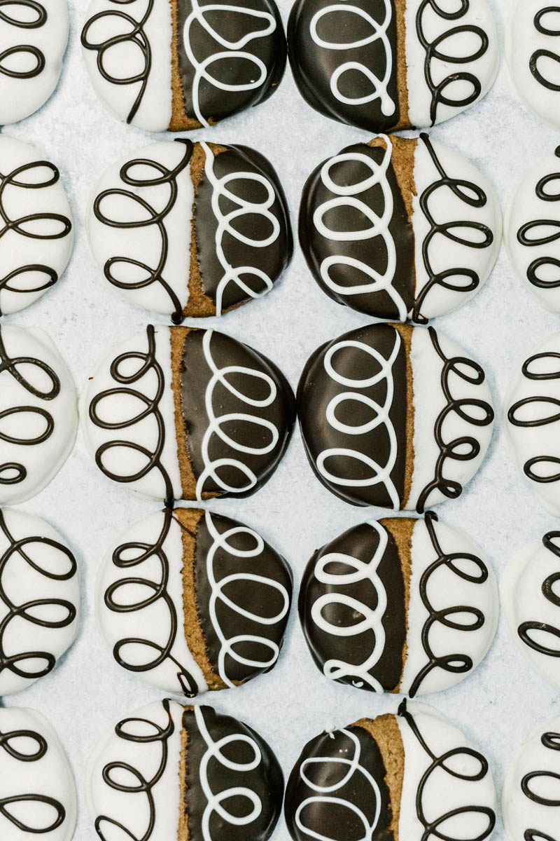 taste before beauty black and white chocolate shortbread cookies on table with white and chocolate drizzles lined up in a row