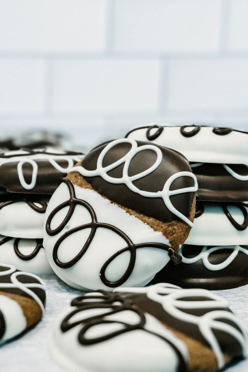 taste before beauty black and white chocolate shortbread cookies on table with white and chocolate drizzles stacked on top of each other