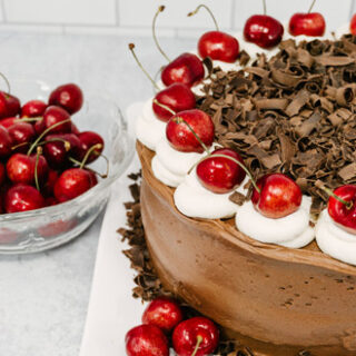 taste before beauty black forest cherry chocolate cake on a plate with cherries on top and chocolate in the middle