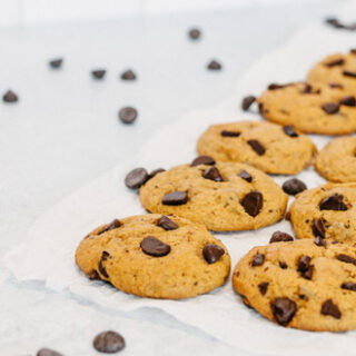 taste before beauty pumpkin chocolate chip cookies on parchment paper with chocolate chips