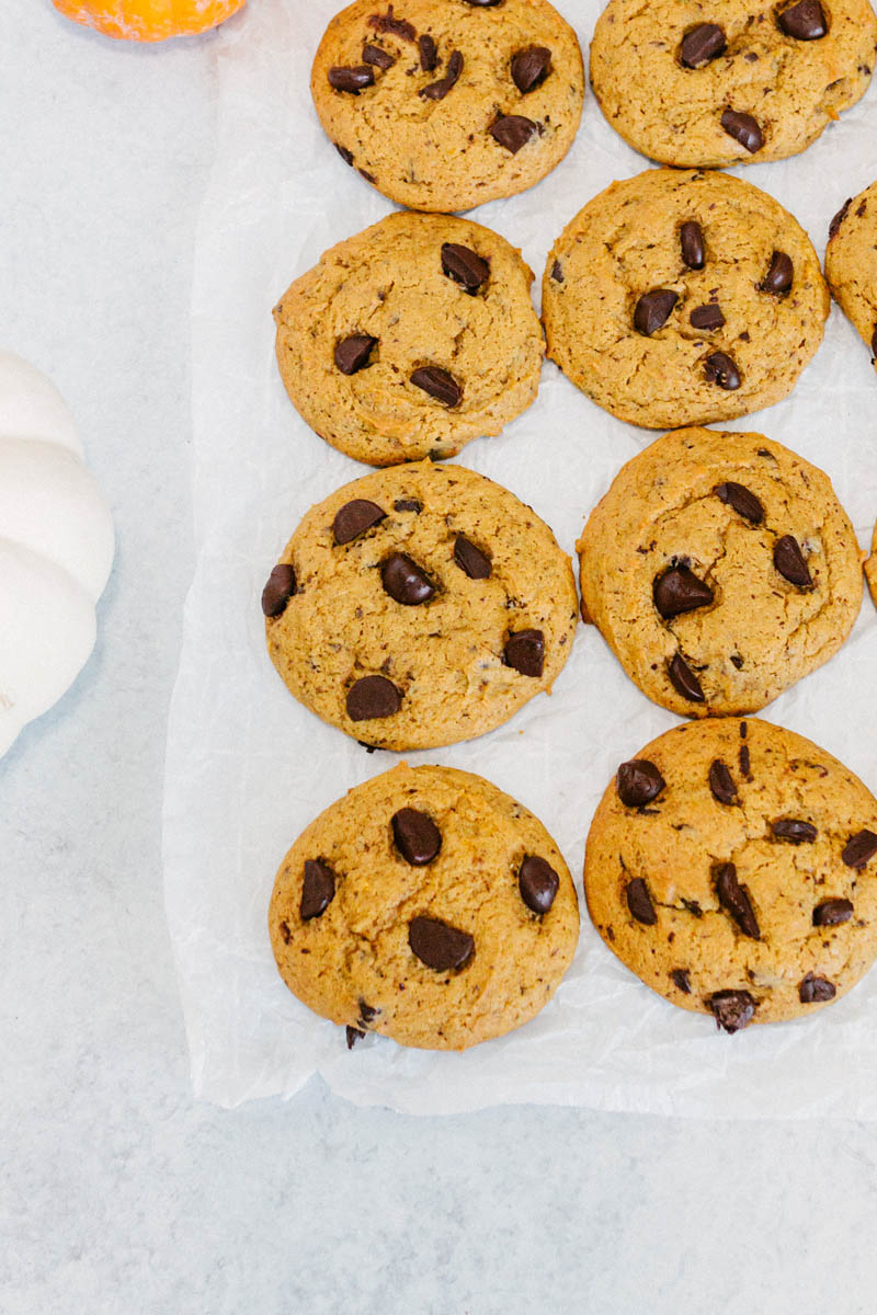 taste before beauty pumpkin chocolate chip cookies on parchment paper with chocolate chips together on parchment paper on the table