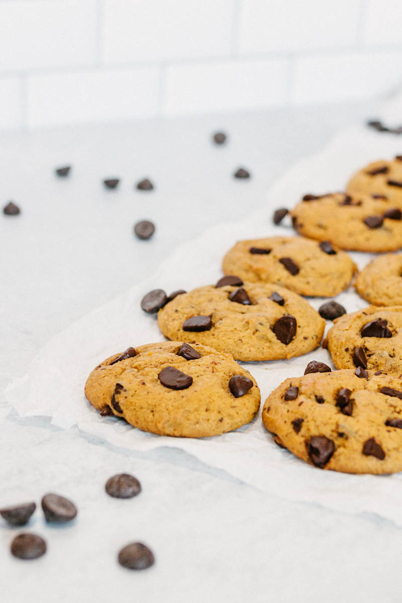 taste before beauty pumpkin chocolate chip cookies on parchment paper with chocolate chips