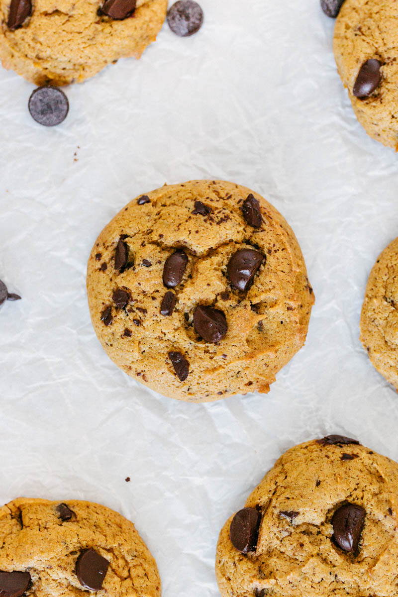 taste before beauty pumpkin chocolate chip cookies on parchment paper with chocolate chips on parchment paper next to each other