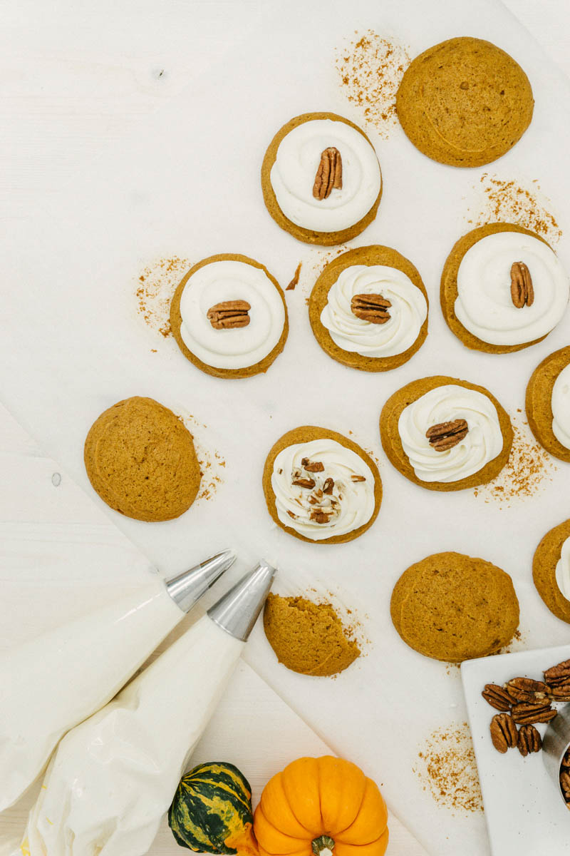 taste before beauty pumpkin cream cheese cookies with walnuts and pumpkins layed out on parchment paper with icing
