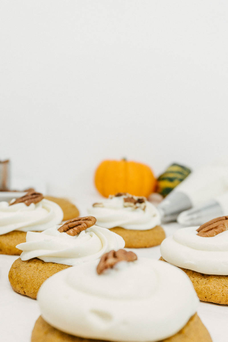 taste before beauty pumpkin cream cheese cookies with walnuts and pumpkins layed out on parchment paper