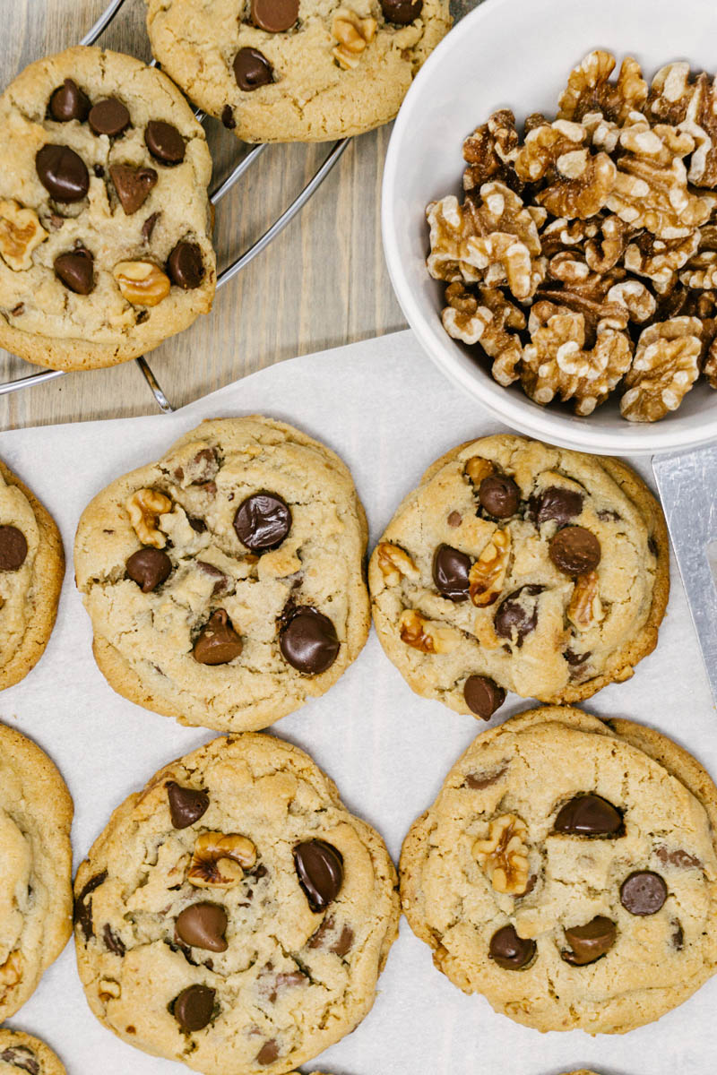 taste before beauty triple chocolate chip walnut cookies on parchment paper on a table with walnuts