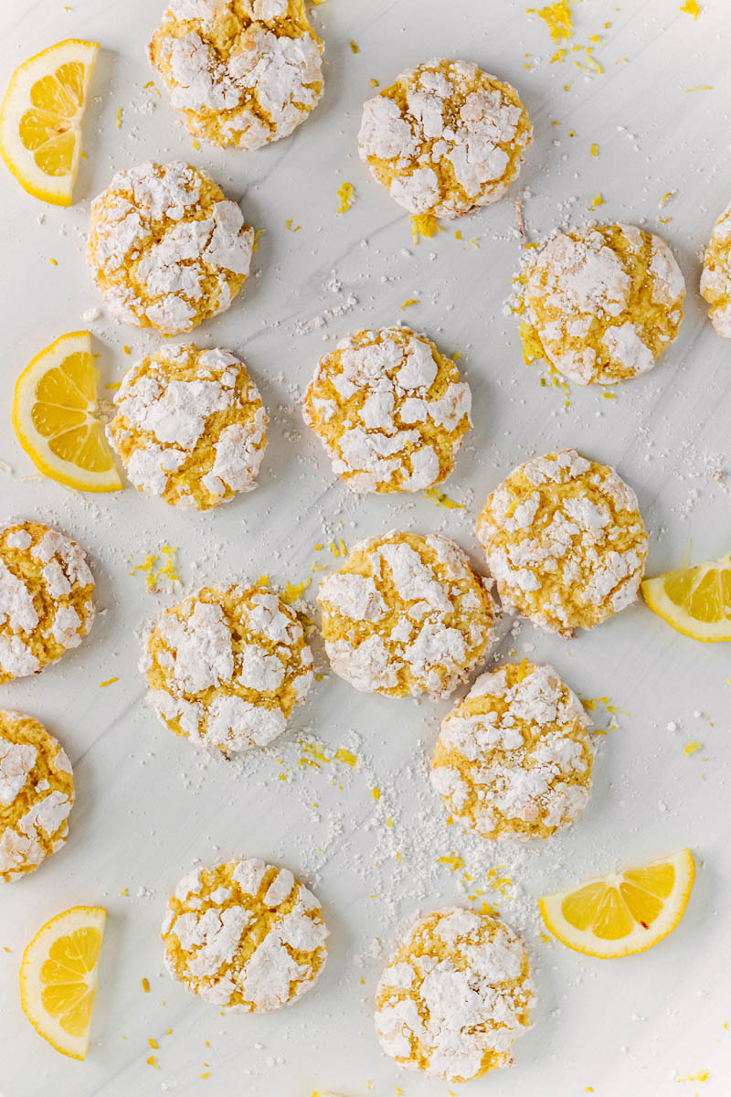 taste before beauty coconut lemon crackle cookies spread on table with lemon zest and powdered sugar