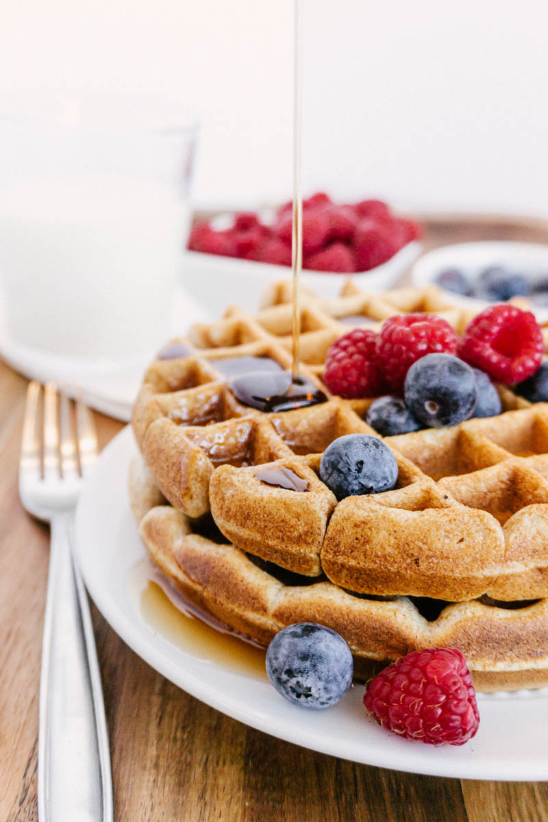 taste before beauty whole wheat waffles on plate with blueberries raspberries milk with syrup pouring and fork