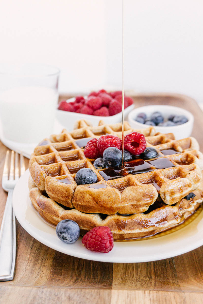 taste before beauty whole wheat waffles on plate with blueberries raspberries milk with pouring syrup