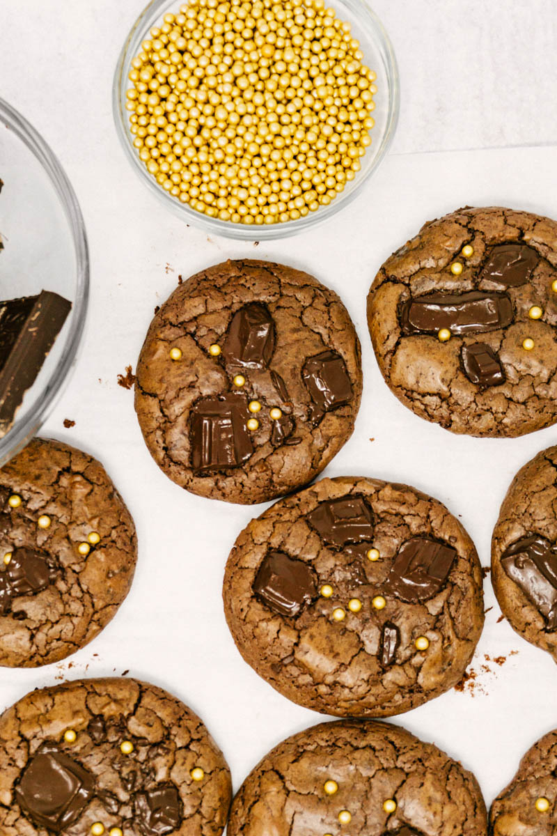 aztec wonder chocolate cayenne cookies on table with gold sprinkles and chocolate