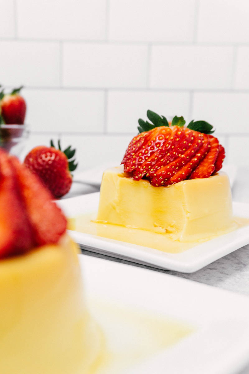 creamy flan on plate with strawberries on table