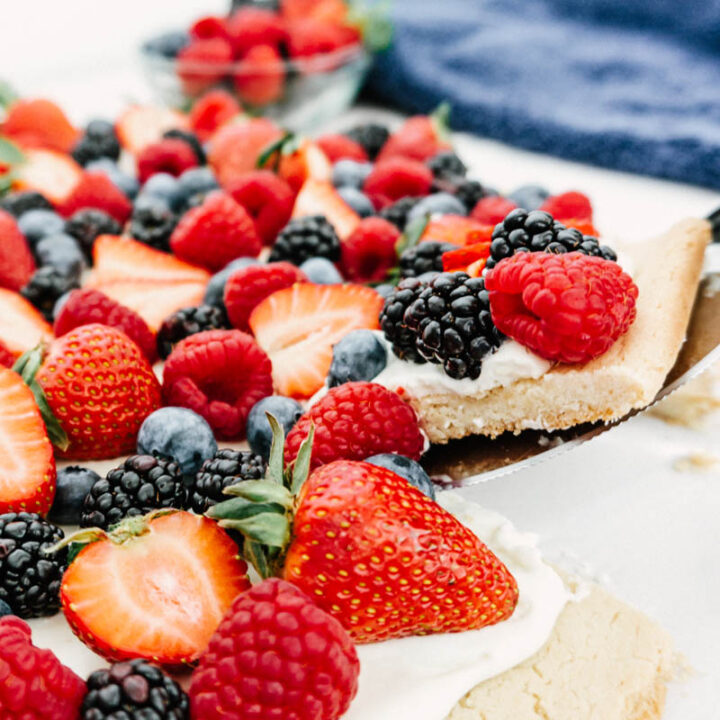 easy fruit pizza with berries pulling out a slice