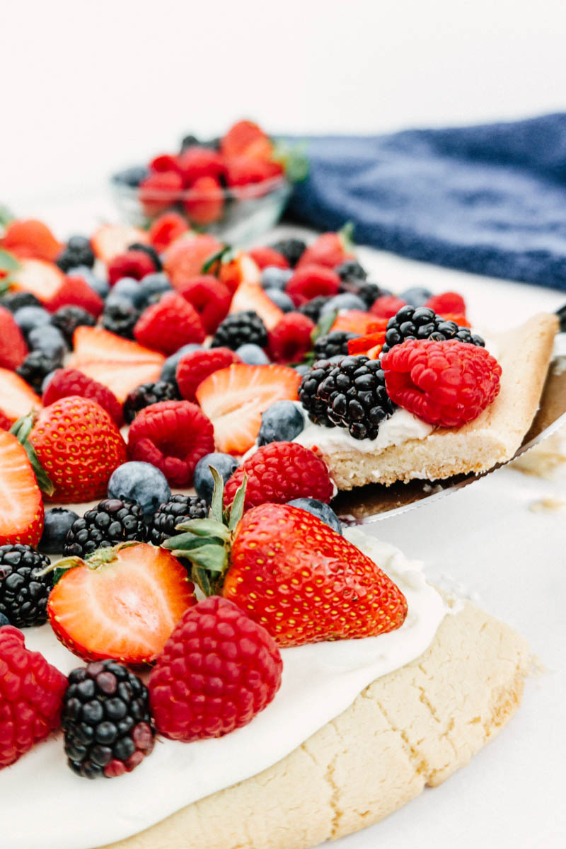 easy fruit pizza with berries pulling out a slice