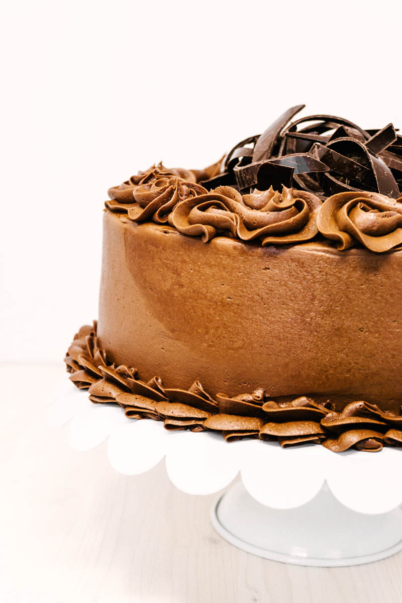 chocolate cake with chocolate buttercream frosting on cake stand