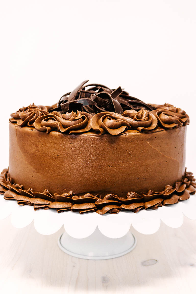 chocolate cake with chocolate buttercream frosting on cake stand on table