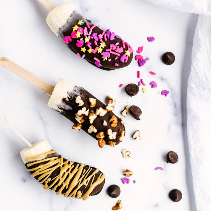 frozen chocolate covered bananas with toppings on the table