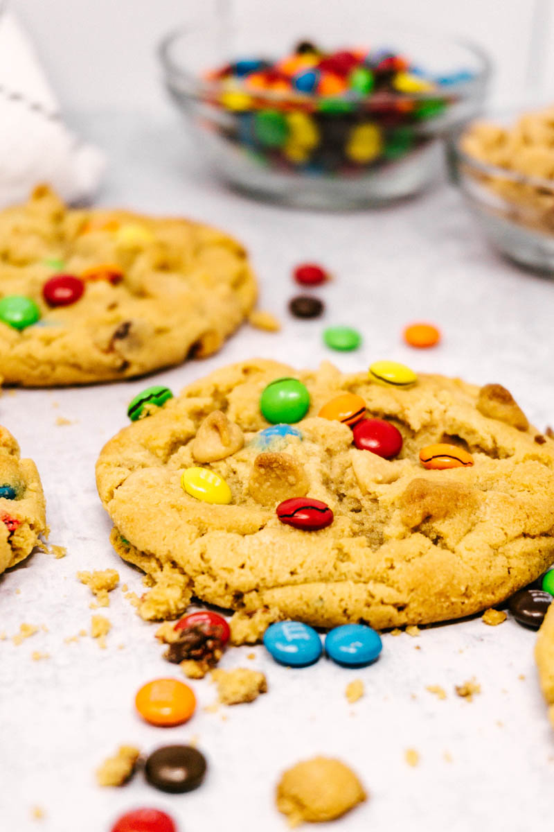 loaded peanut butter cookies on table with m&ms in a glass dish