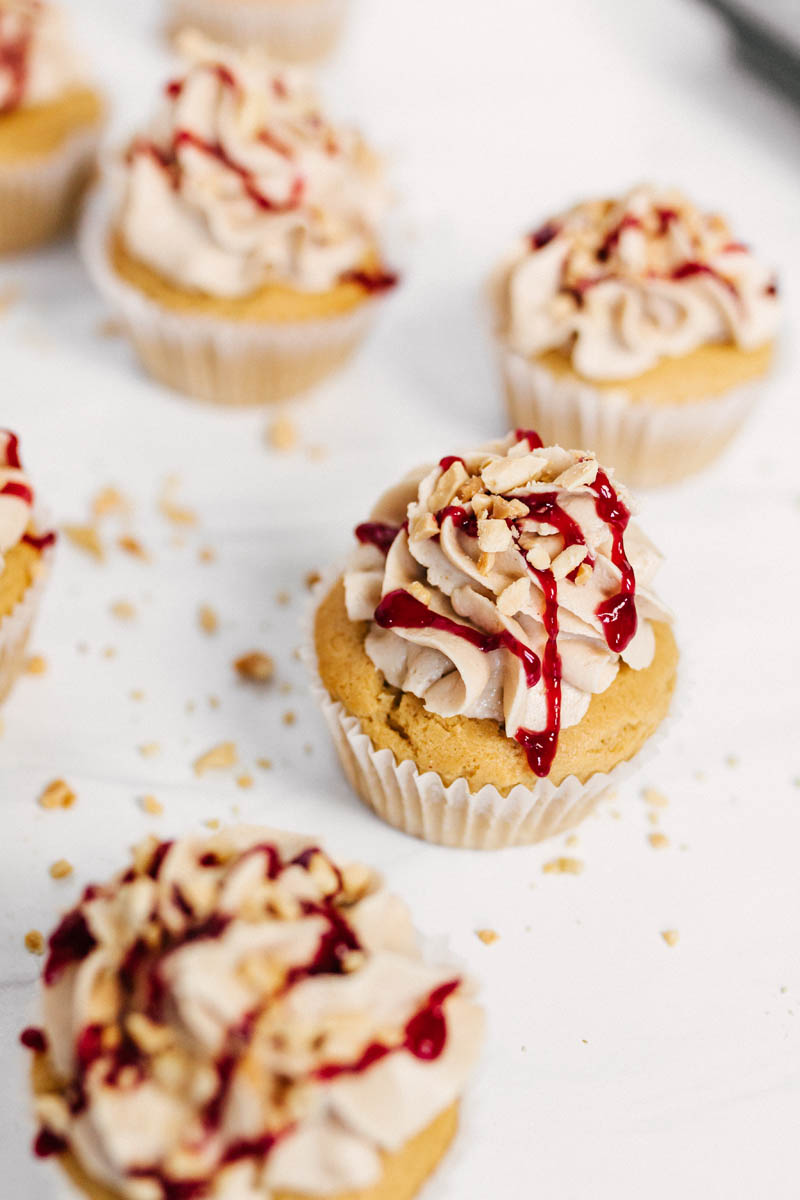 peanut butter and jelly cupcakes on a table with peanuts