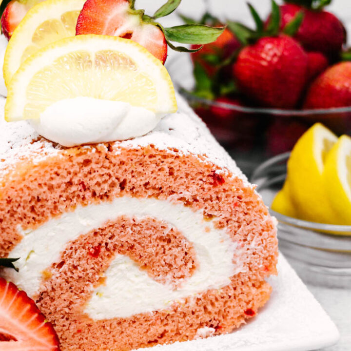 strawberry lemon cake roll on plate with lemons and strawberries