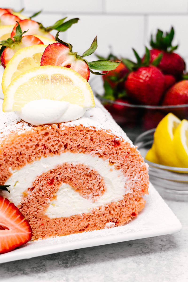 strawberry lemon cake roll on plate with lemons and strawberries