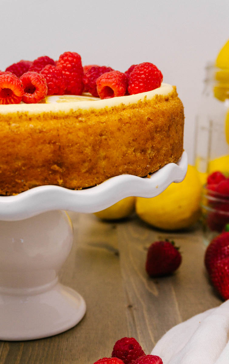new york cheesecake on a cake stand with raspberries