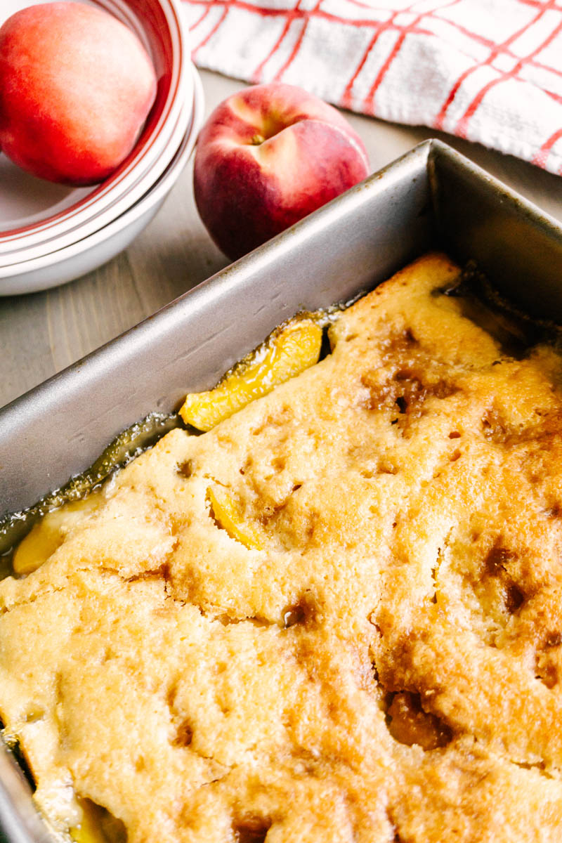 peach cobbler in pan with peaches