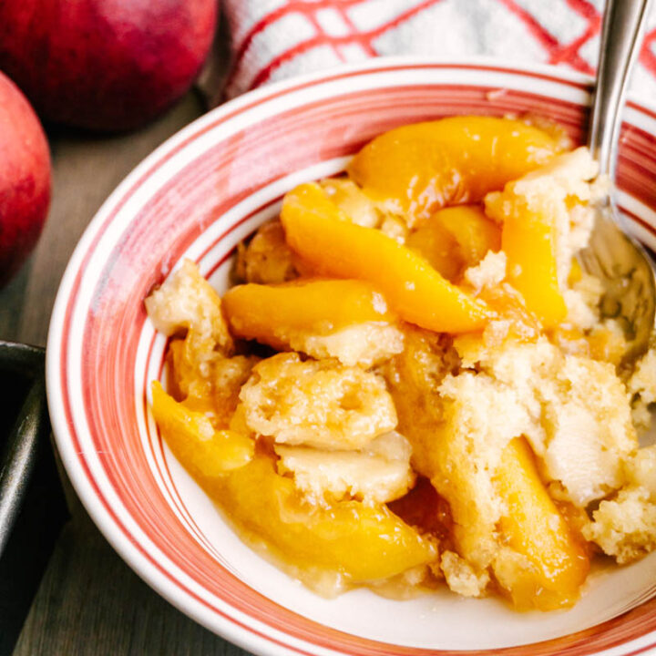 peach cobbler with peaches and a spoon in a bowl