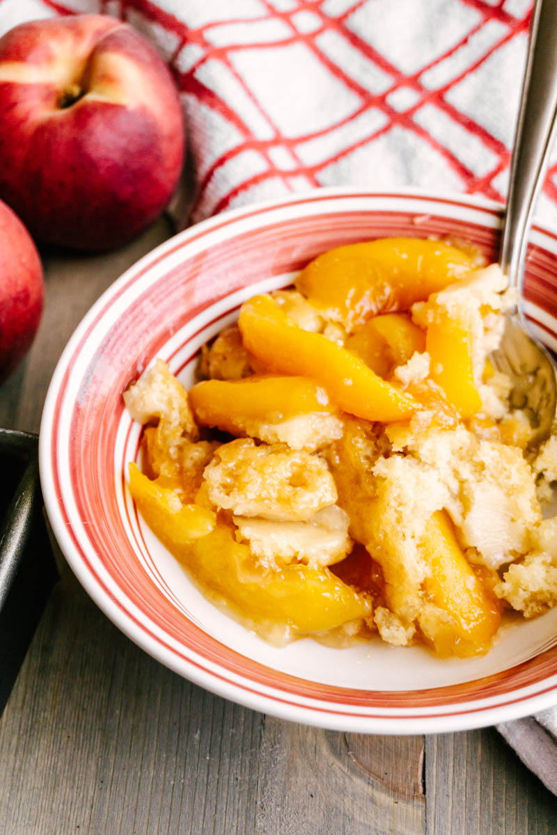 peach cobbler with peaches and a spoon in a bowl