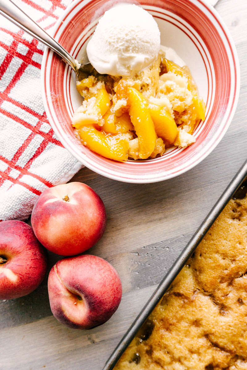 peach cobbler in pan and a bowl on the table