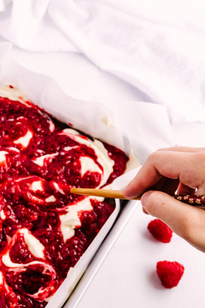 raspberry cheesecake brownies being swirled before baking