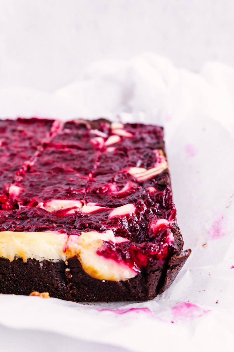 raspberry cheesecake brownies baked and on parchment paper