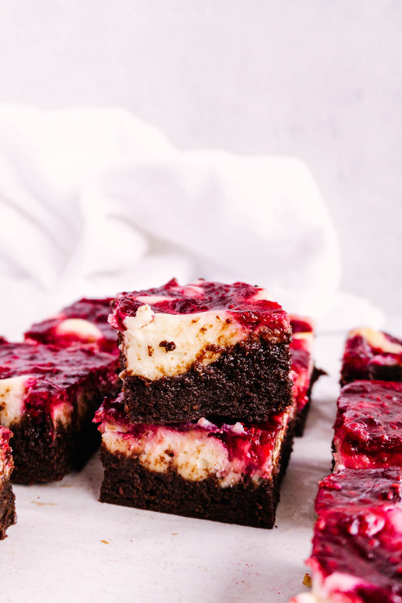 raspberry cheesecake brownies stacked on table
