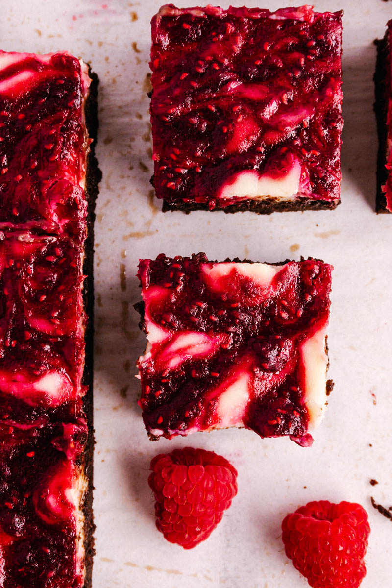 raspberry cheesecake brownie squares with raspberries on the table