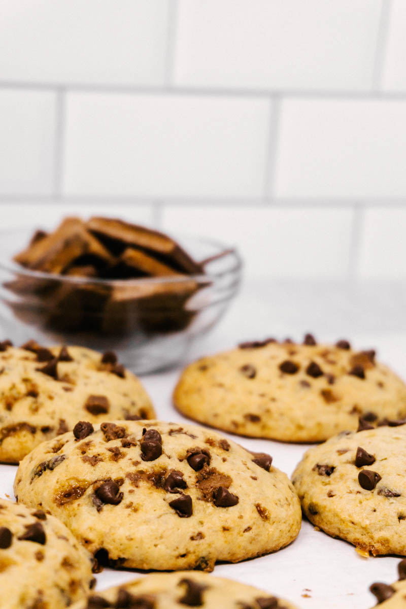 banana toffee chocolate chip cookies laid on the table with chocolate in the back