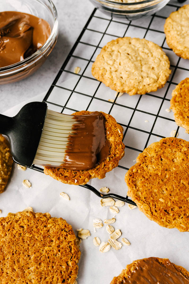 copycat hobnobs oatmeal crumble cookies being spread with chocolate coating