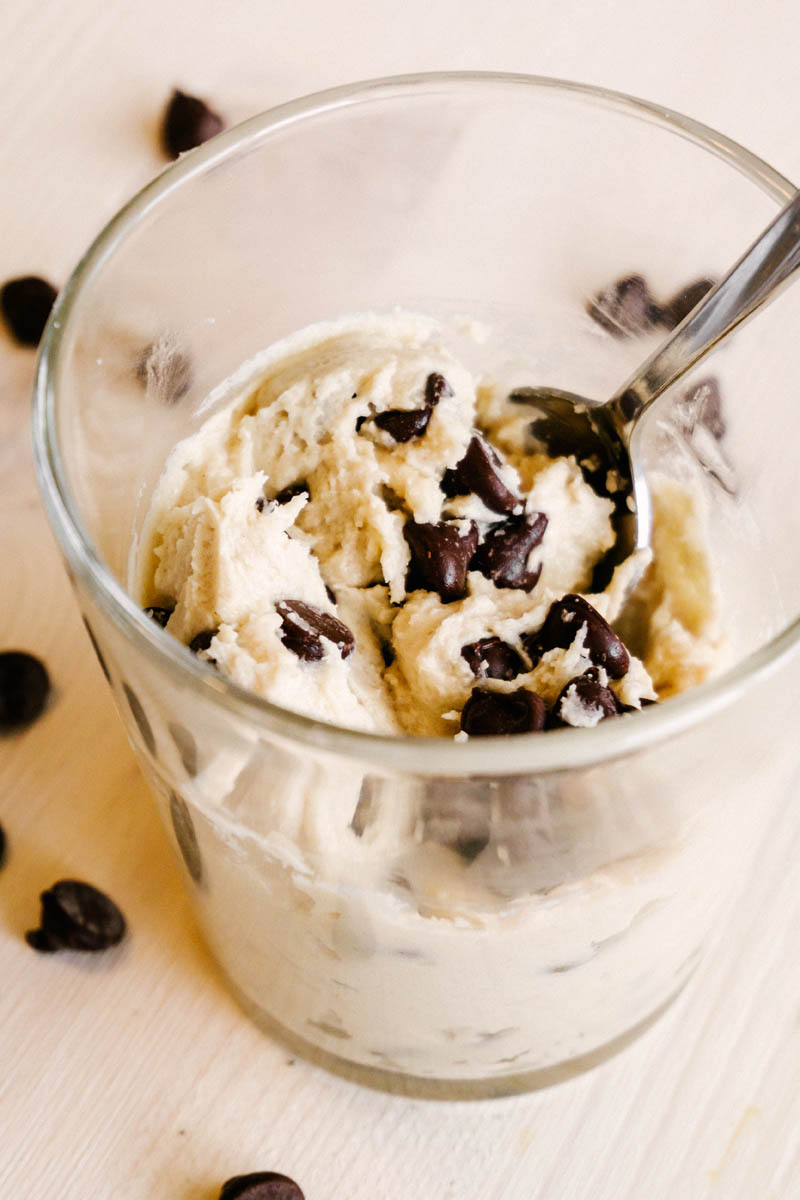 edible cookie dough in a glass with chocolate chips and a spoon