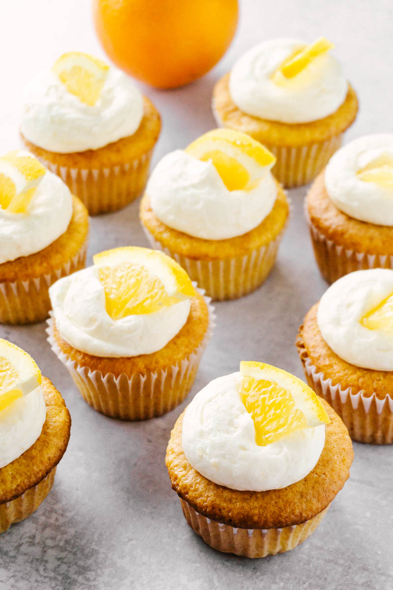 multiple orange cream cupcakes spread out on the counter