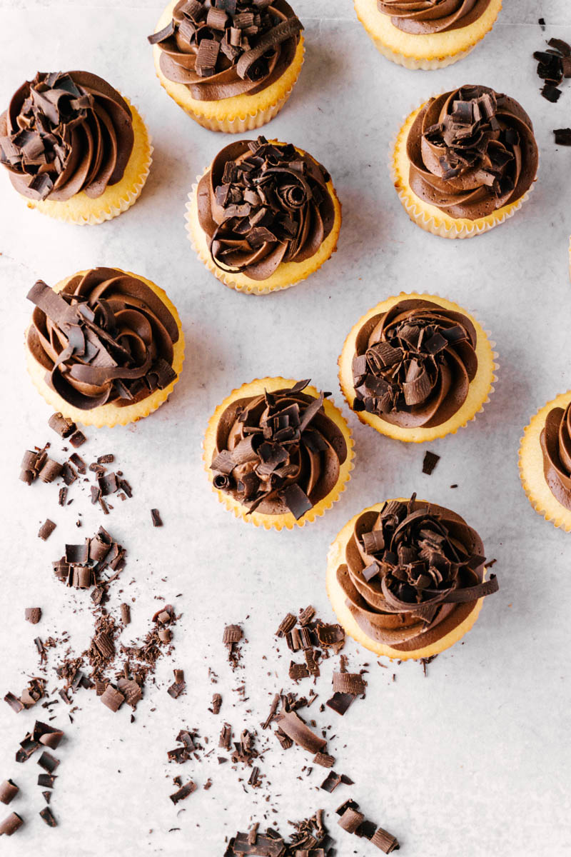 yellow cupcakes with chocolate buttercream frosting and chocolate topping on the table