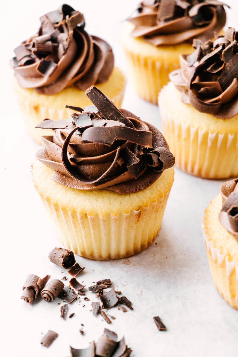 yellow cupcakes with chocolate buttercream frosting placed on the table