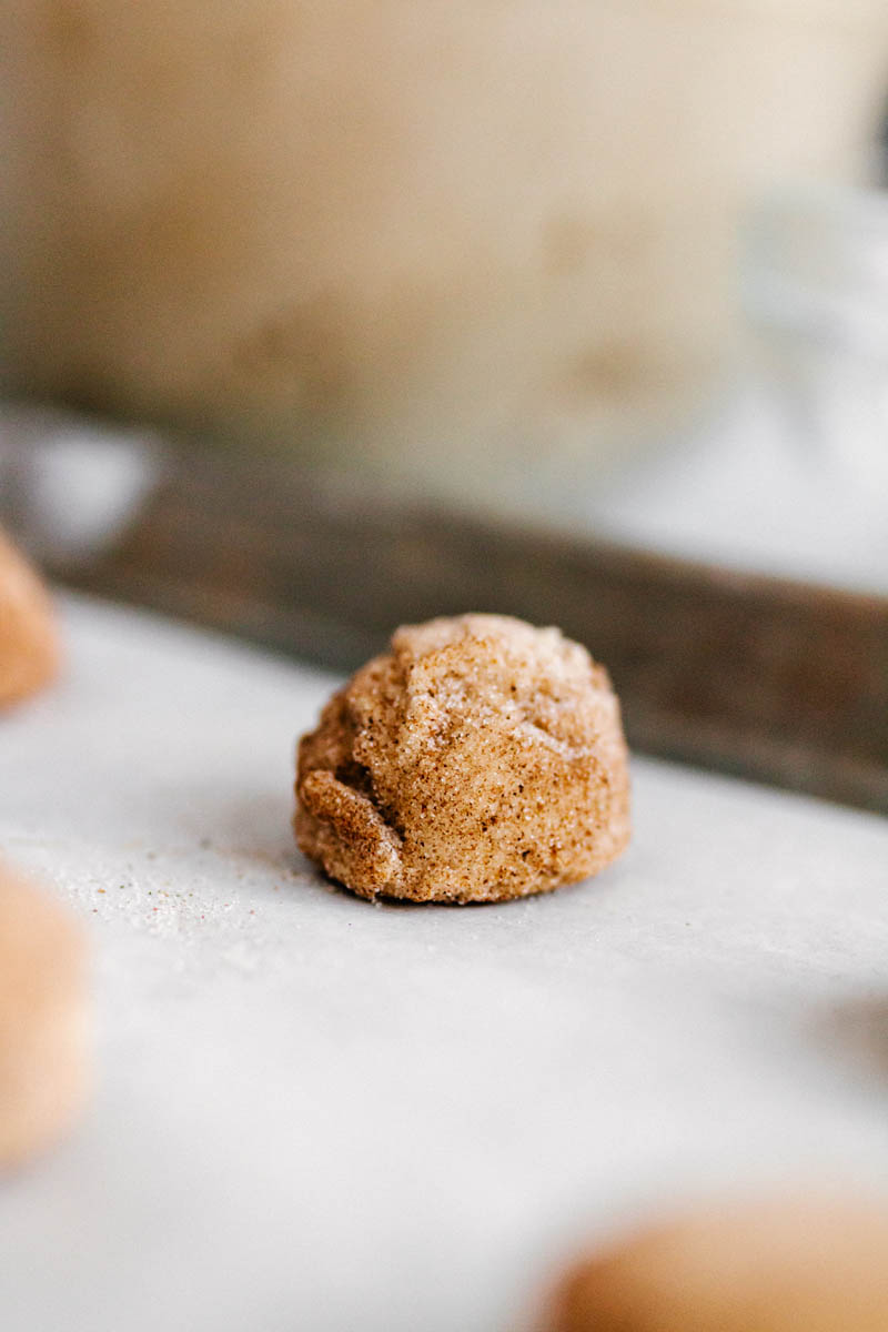 a chai sugar cookie dough rolled into sugar and chai spice mix on a baking sheet