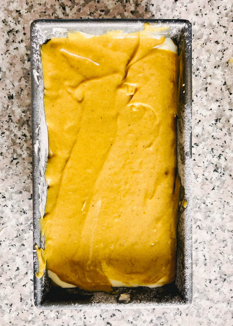 pumpkin bread batter layered with batter on top in a loaf pan