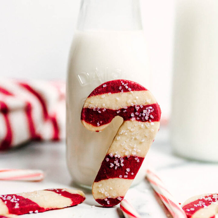 peppermint candy cane shortbread cookie leaning against a bottle full of milk