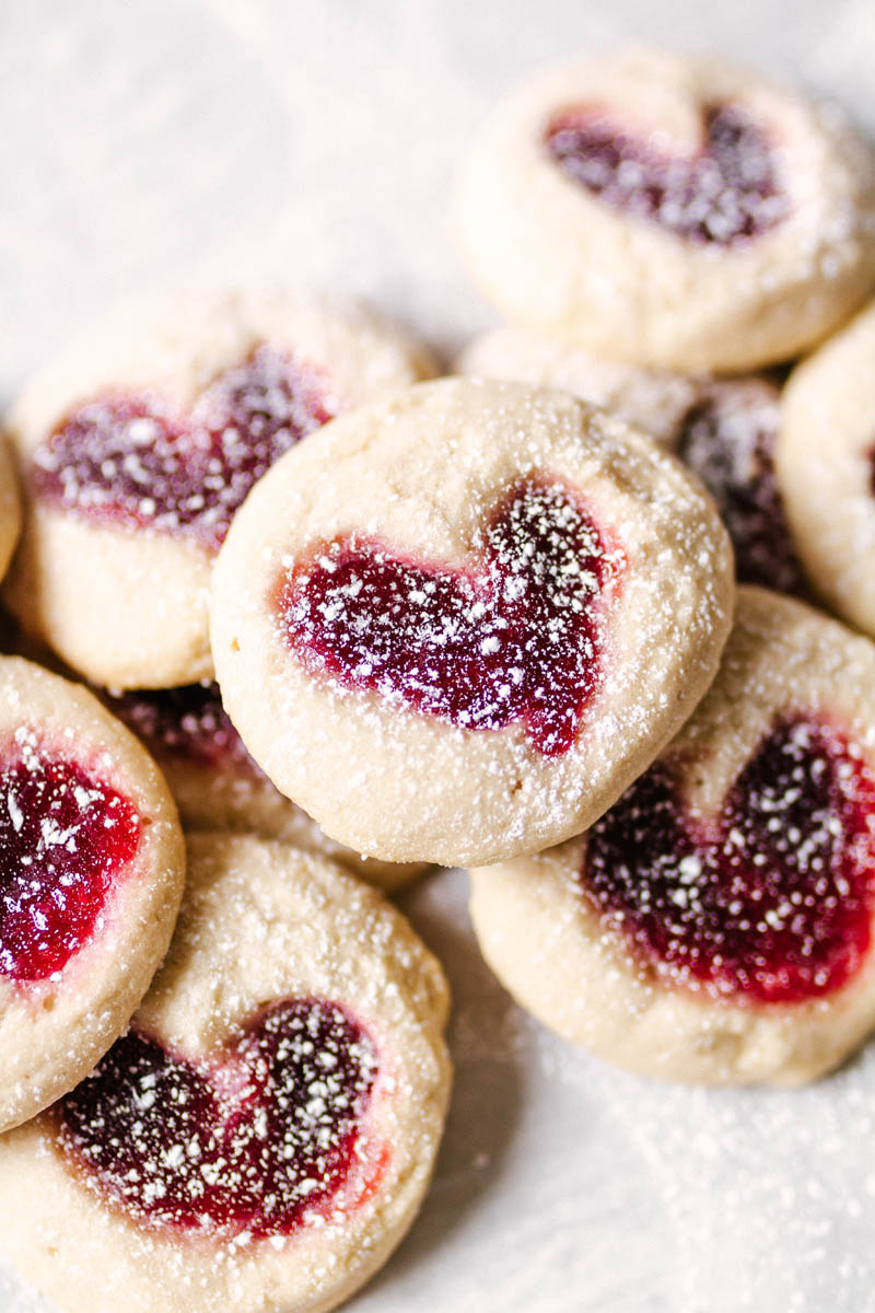 heart thumbprint cookies stacked on top of each other with powdered sugar coating