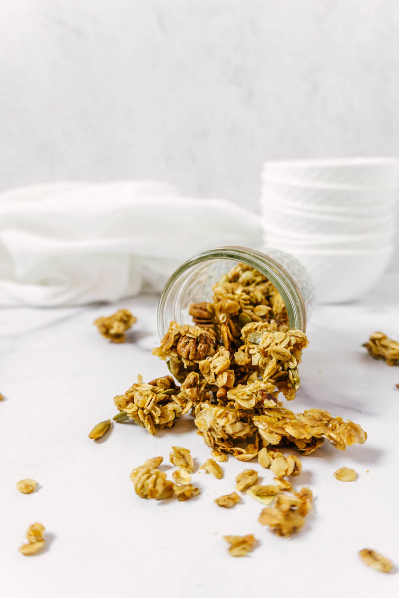 granola in a glass jar that is tipped over spilling out