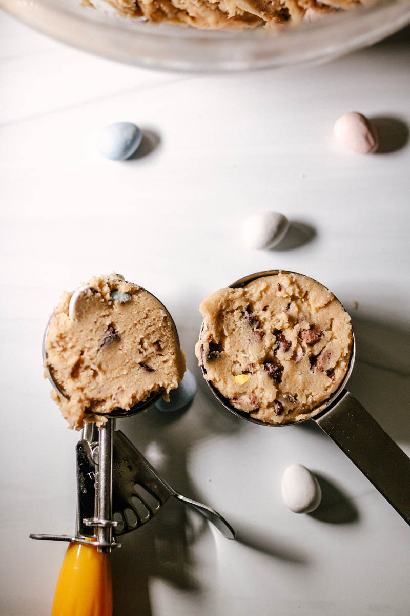 cookie dough in a #20 cookie dough scoop and next to it a 1/4 cup filled with cookie dough